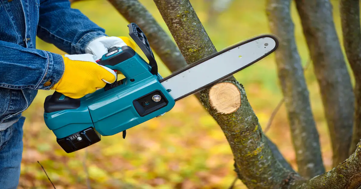 Man using electric chainsaw to reduce fossil fuels