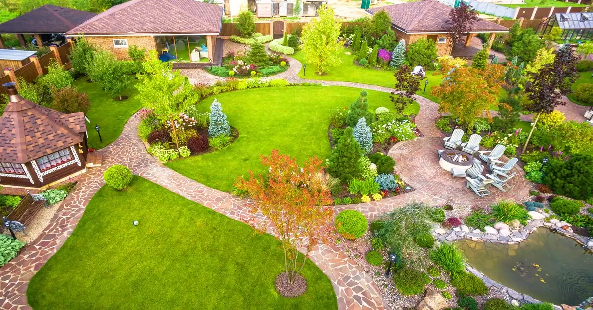 Large garden design complete with small pond, walkways and plants in backyard of a home.