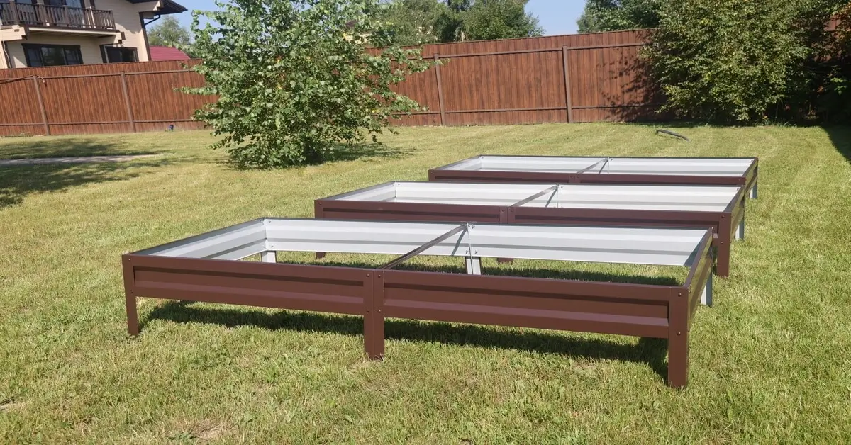 Three brown brand new metal raised beds in yard ready to use.