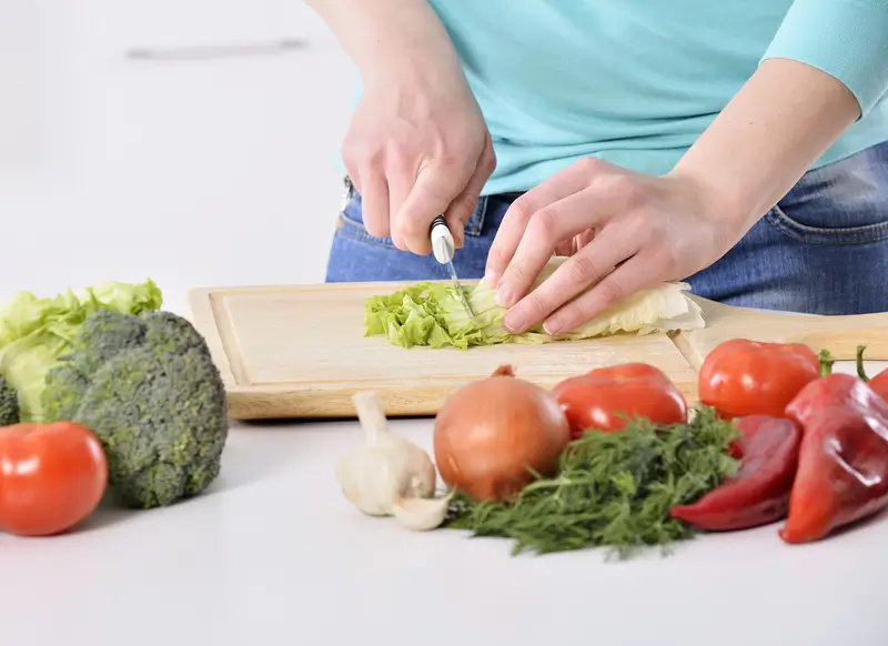 Woman preparing vegetables on counter from her kitchen garden.